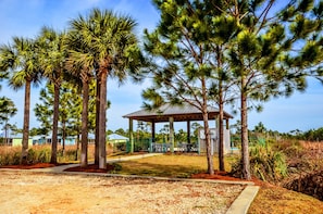 A gazebo with a roof, surrounded by tall trees and a pathway.