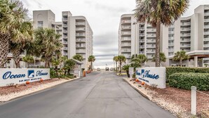 En hotellentrén med två höga byggnader, palmer och en skylt med texten ”Ocean House 949 West Beach Blvd.”