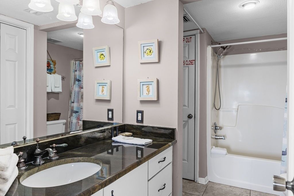 Un bany amb un mirall gran, un lavabo i una dutxa.