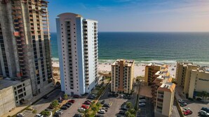 A high-rise hotel with a view of the ocean, parking lots, and beach access. - Clearwater Unit 7C (Gulf Shores)