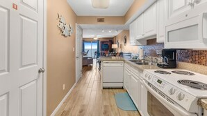 Una cocina con armarios blancos, lavavajillas, estufa y alfombra azul.