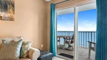 A room with a sofa, a small table, and a view of a balcony with outdoor furniture.