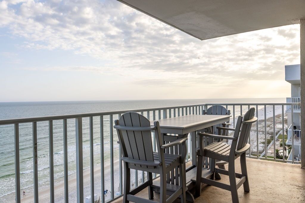 Un balcon avec une table et des chaises donnant sur l’océan.