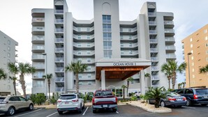Un hôtel à plusieurs étages, doté d’une entrée imposante portant l’inscription « Ocean House I » et d’un parking où sont stationnées plusieurs voitures.