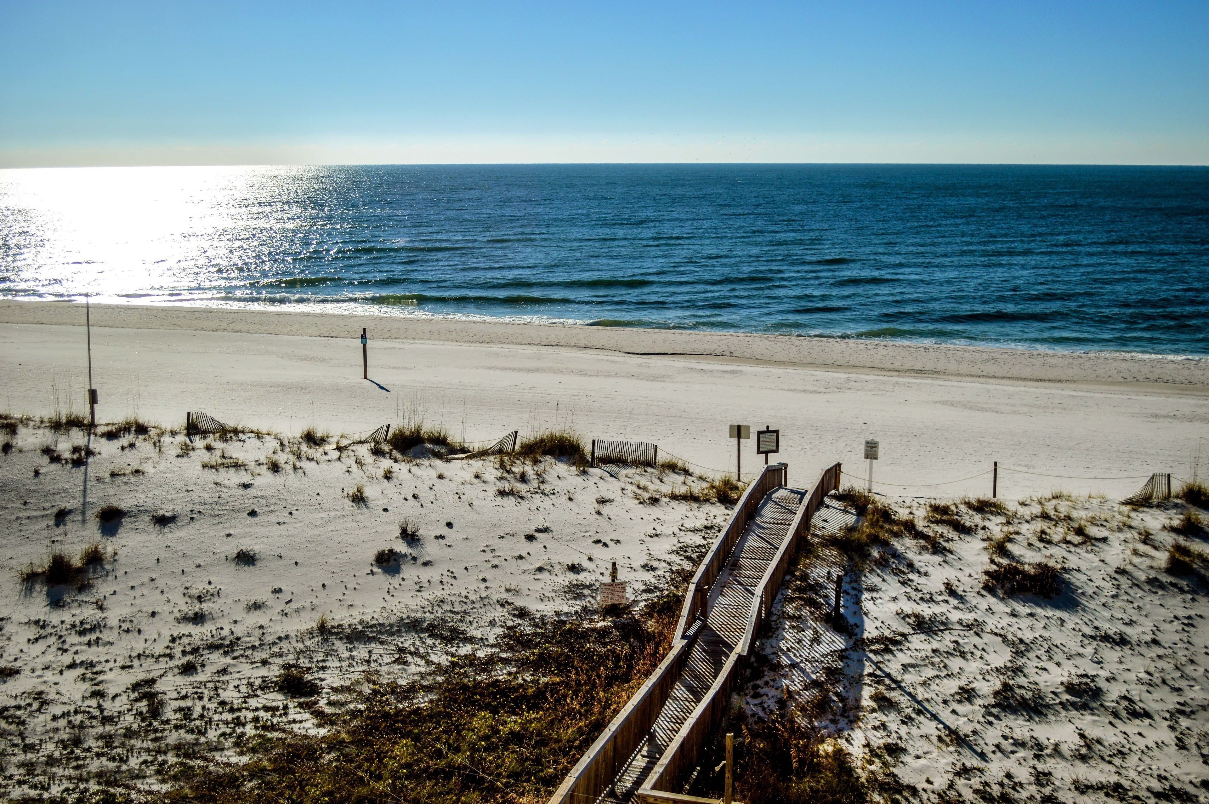 A beach with a wooden boardwalk leading to the ocean.