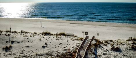 A beach with a wooden boardwalk leading to the ocean.