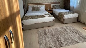 Una habitación de hotel con dos camas, un armario de madera, un tapete estampado y un cuadro colgado en la pared.