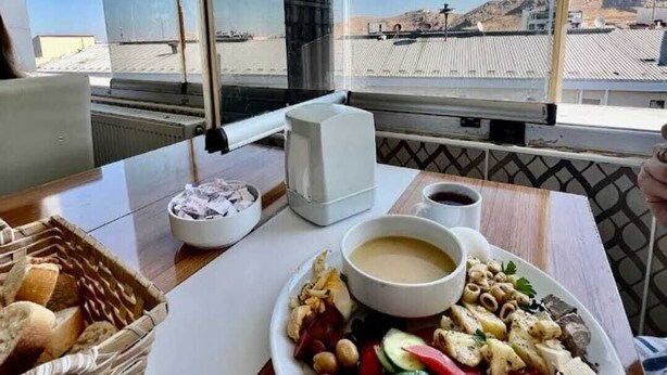 Una mesa con un plato de comida, un bol de sopa y una cesta de pan.