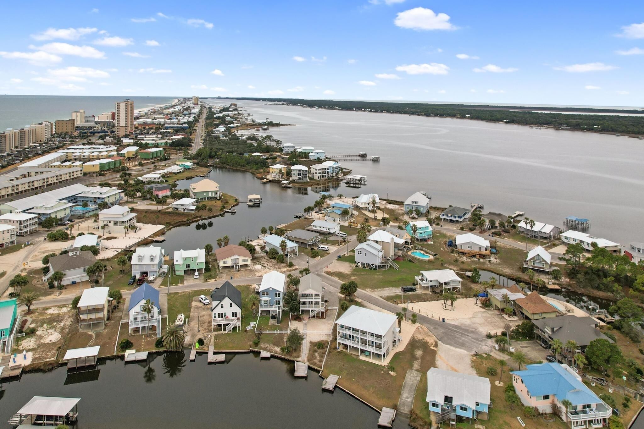 Vista aérea de una zona residencial costera con casas, muelles y un puerto deportivo.