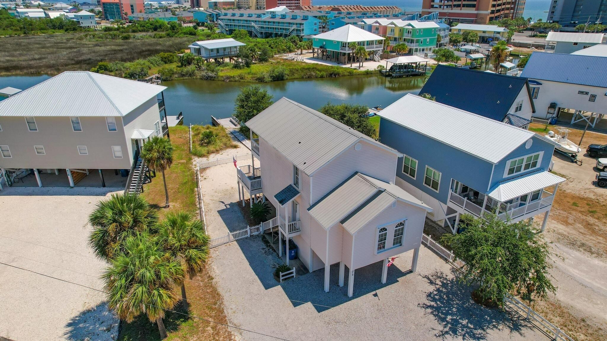 A coastal residential area with houses near a water body, featuring a mix of single and multi-story buildings, some with balconies and waterfront views.