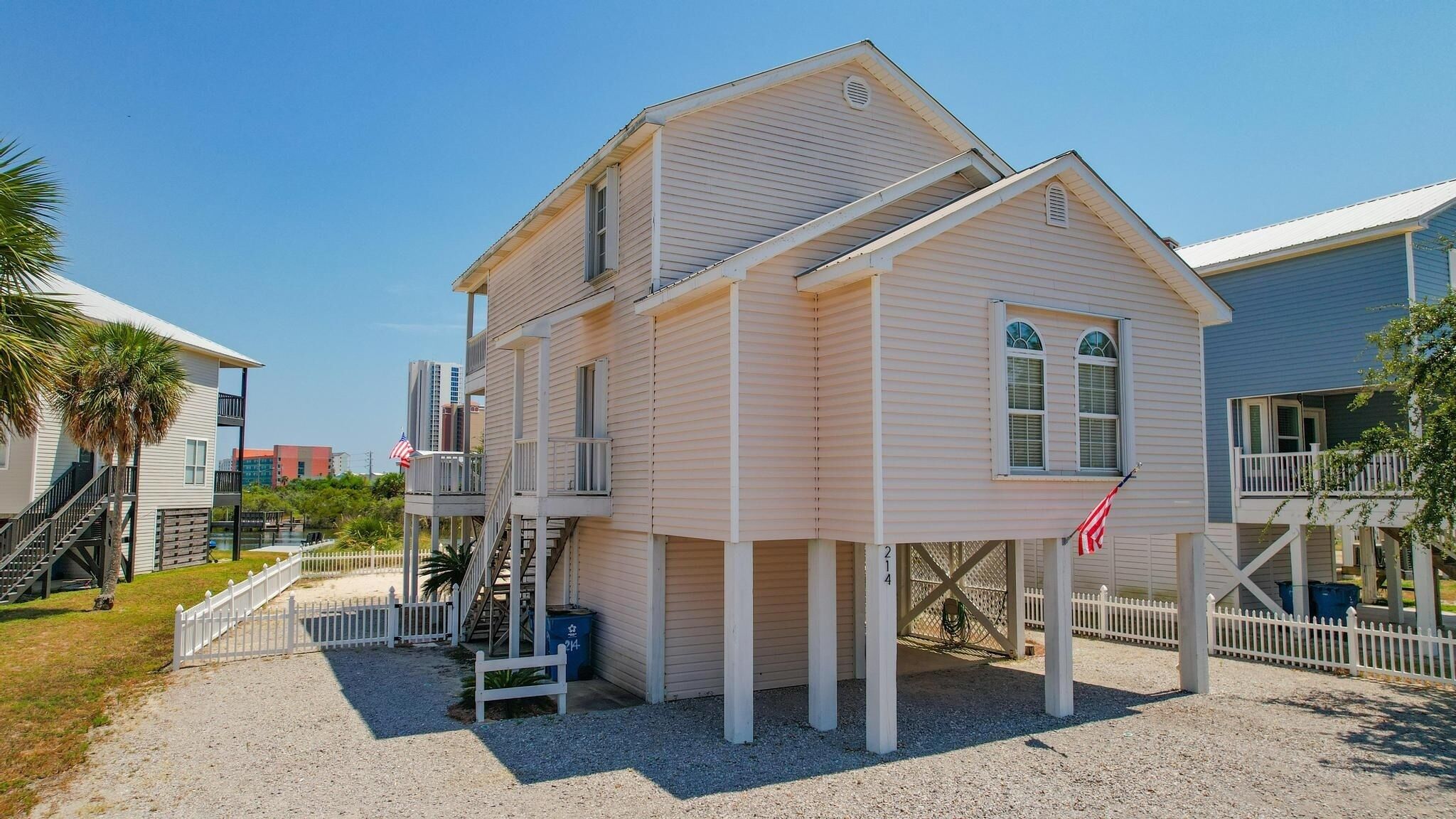 A two-story house with a balcony and a small porch, surrounded by a white picket fence.
