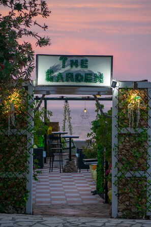 An outdoor seating area with a checkered floor, tables, chairs, and a sign reading "The Garden".
