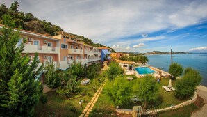 Un hotel frente al mar con varios balcones, piscina y jardín.