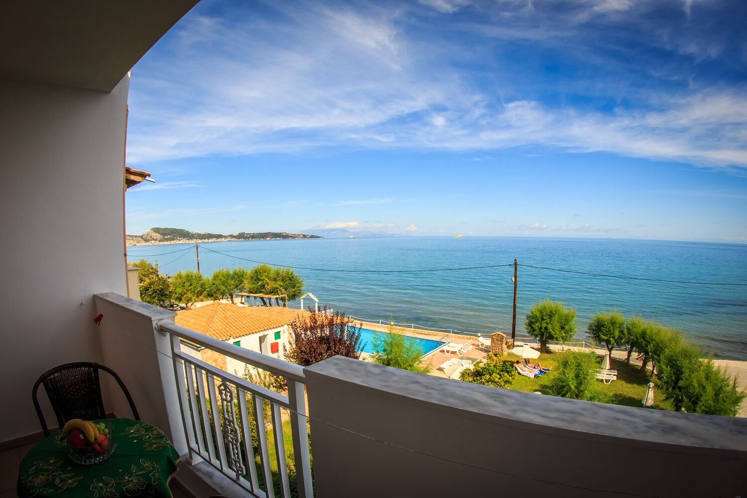 Uma varanda com vista para o mar, uma piscina e uma cadeira.