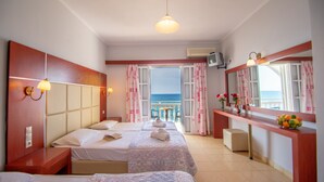 Habitación de hotel con dos camas, un balcón con vistas al mar, una kitchenette pequeña y un baño.