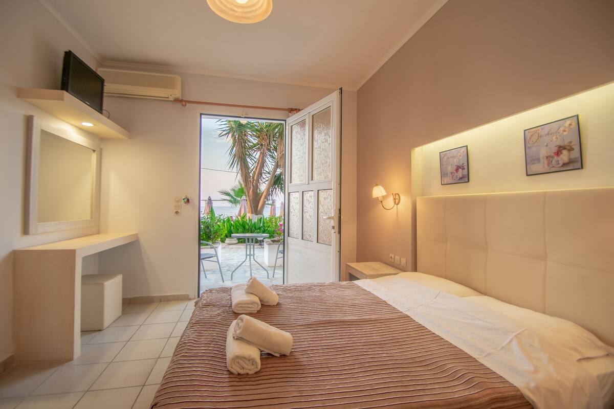 A hotel room with a bed, a desk, a chair, and a view of the outdoors.