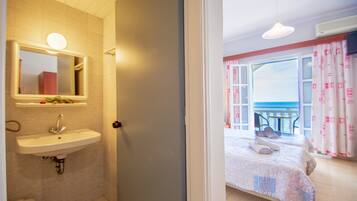 A bathroom with a sink and mirror, a door leading to a balcony with a view.