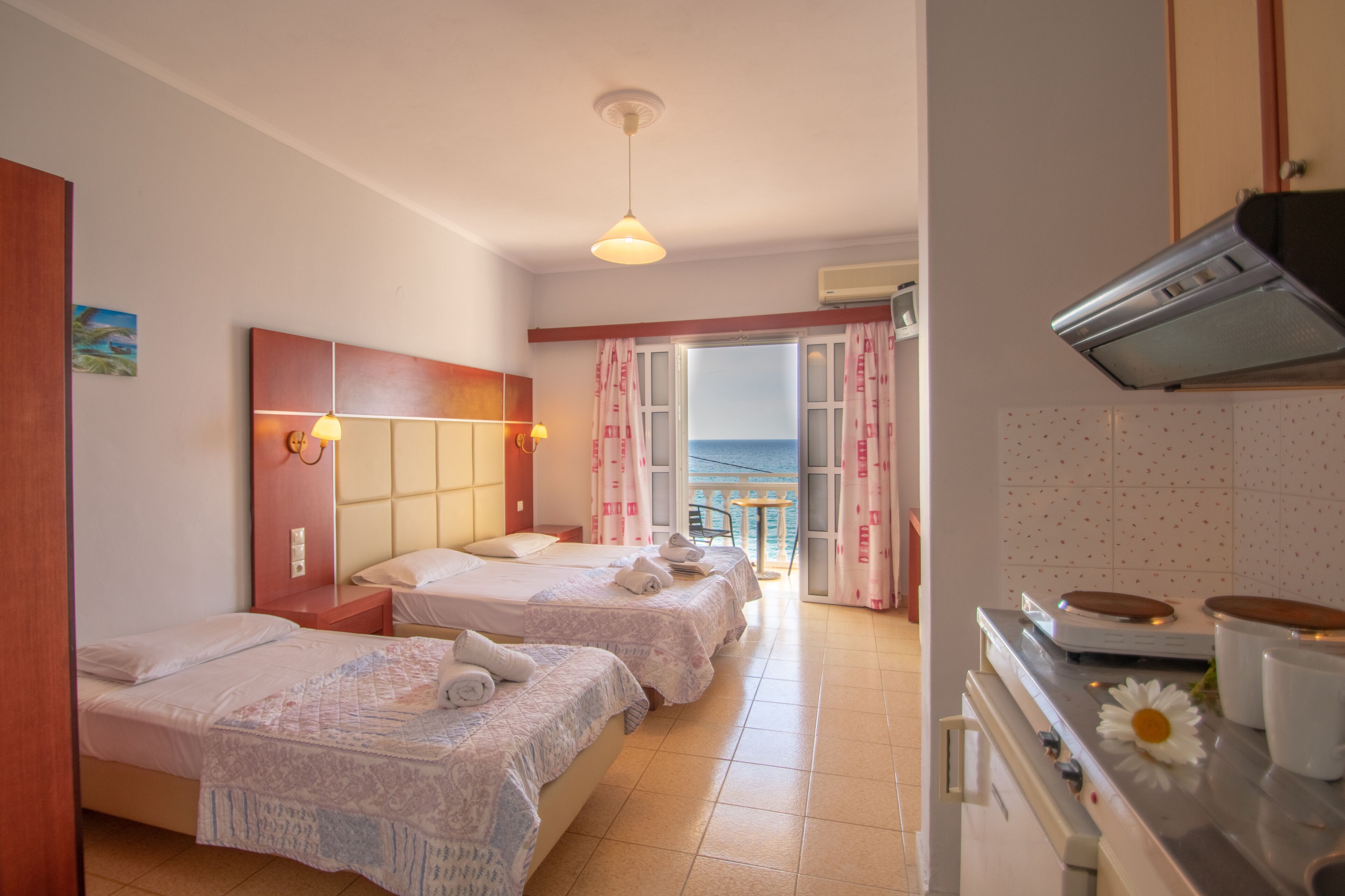 Ein Hotelzimmer mit zwei Betten, einer Küchenzeile und einem Balkon mit Blick.