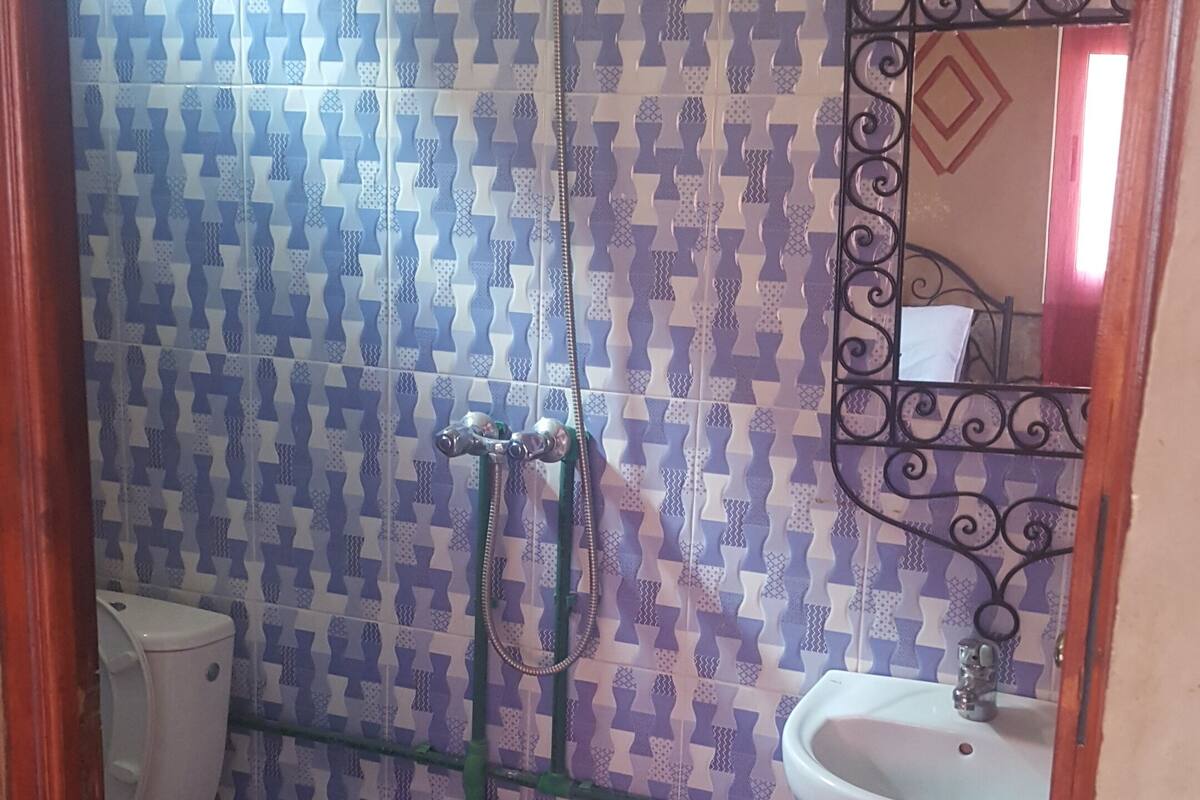 A bathroom with patterned tiles, a shower, a toilet, and a sink with a mirror.