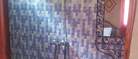 Un baño con azulejos estampados, una ducha, un inodoro y un lavabo con espejo.