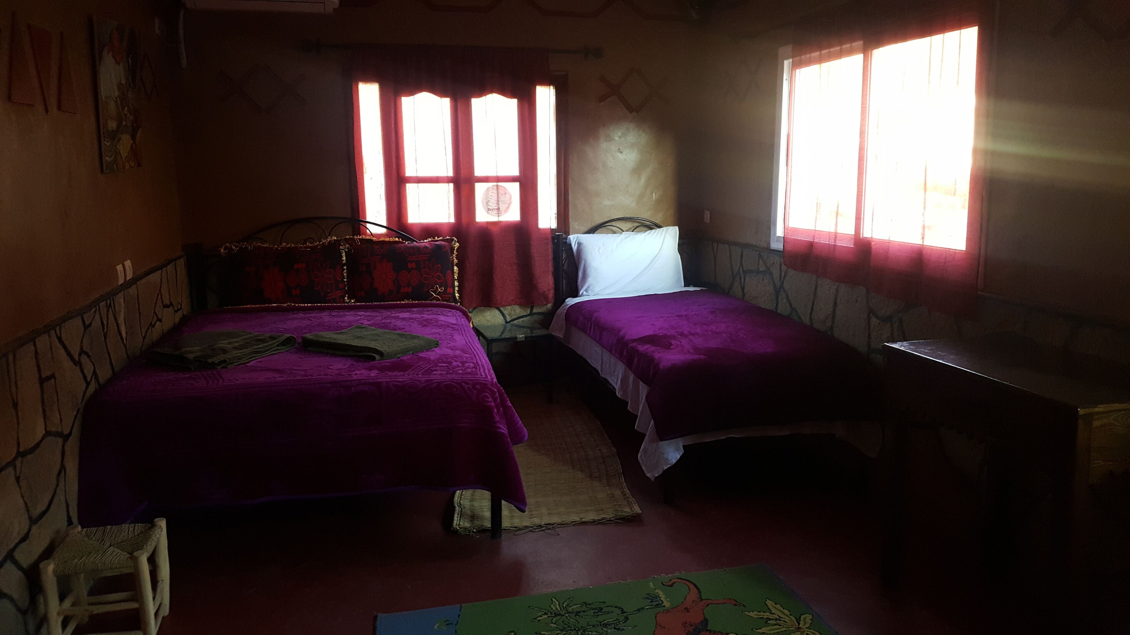 A room with two beds, a small table, and a window.