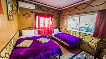A room with two beds, a window with a view, and a patterned rug.