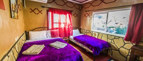 Una habitación con dos camas, un ventanal y un tapete estampado.