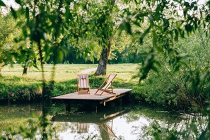 Relax on the riverside dock with two lounge chairs, surrounded by lush greenery.