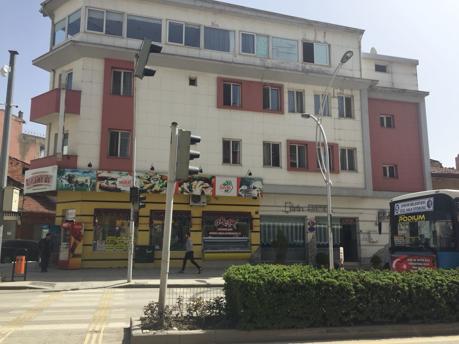 A multi-story building with various shops on the ground floor, including a kebab shop and a cafe.