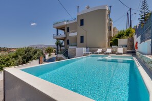 A modern building with a swimming pool, multiple balconies, and a clear view of the surrounding landscape.