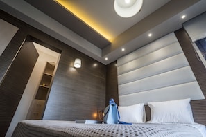 A modern hotel room with a large bed, a bedside table, and a wardrobe.