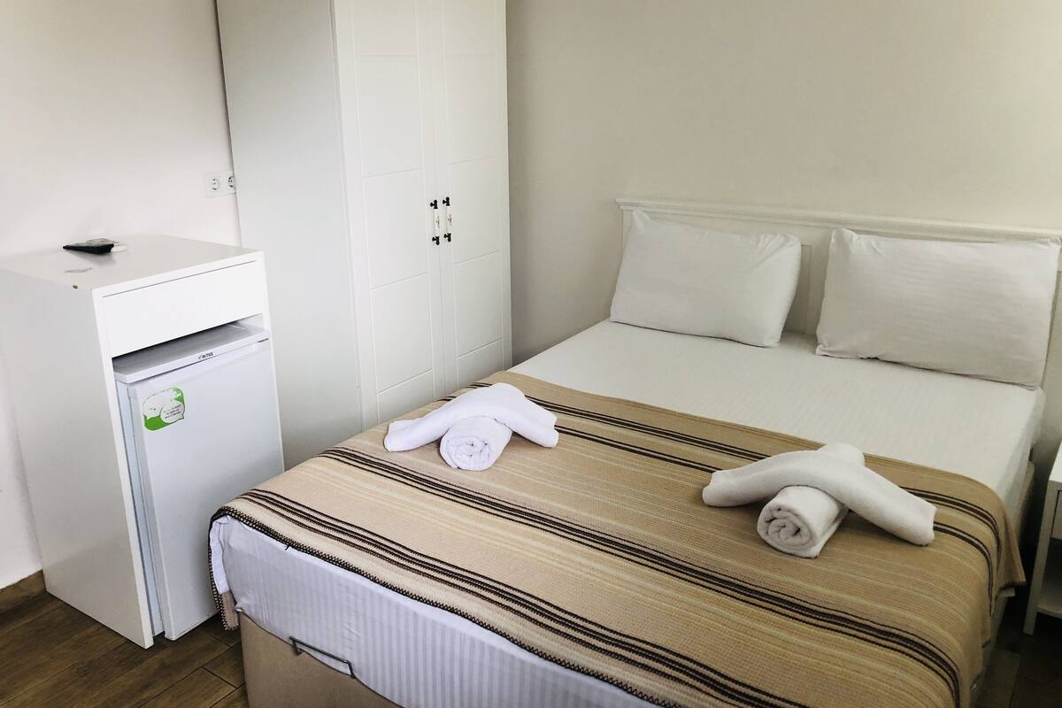 Una habitació d'hotel amb un llit, un petit escriptori i un armari.