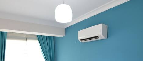 A hotel room with two single beds, a white nightstand, a ceiling fan, and an air conditioning unit.