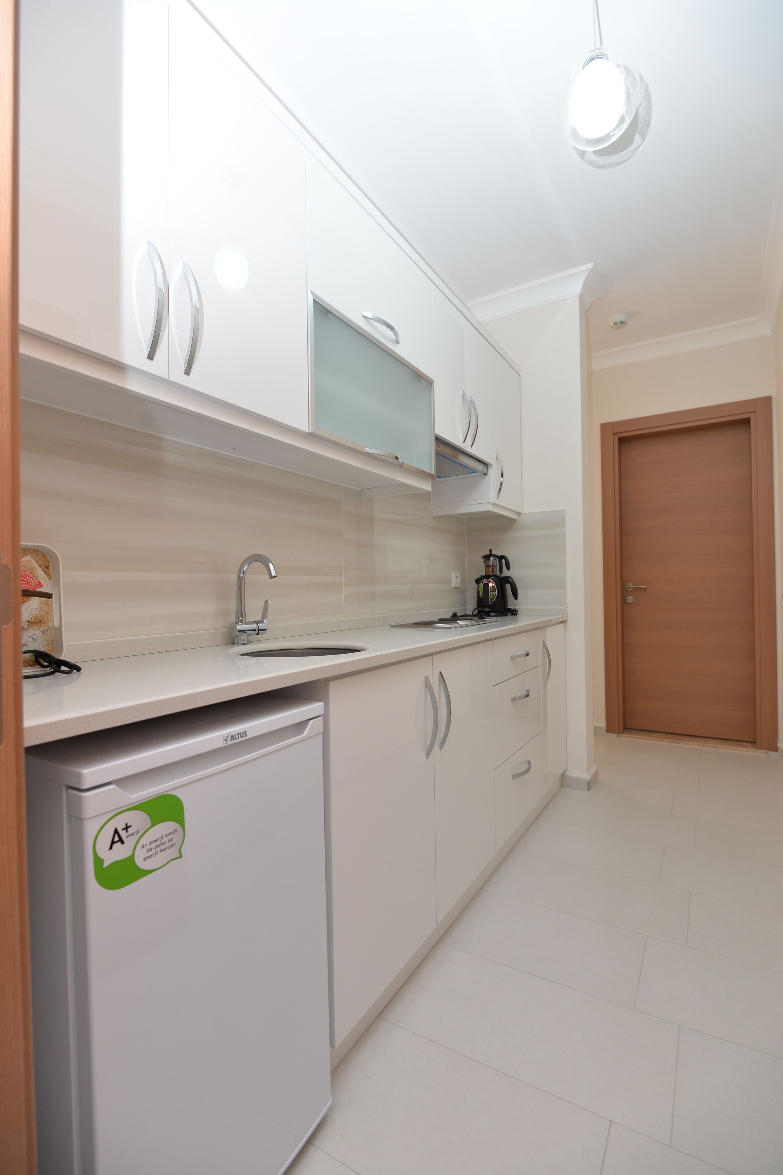 A modern kitchen with white cabinets, a dishwasher, and a coffee maker on the counter.
