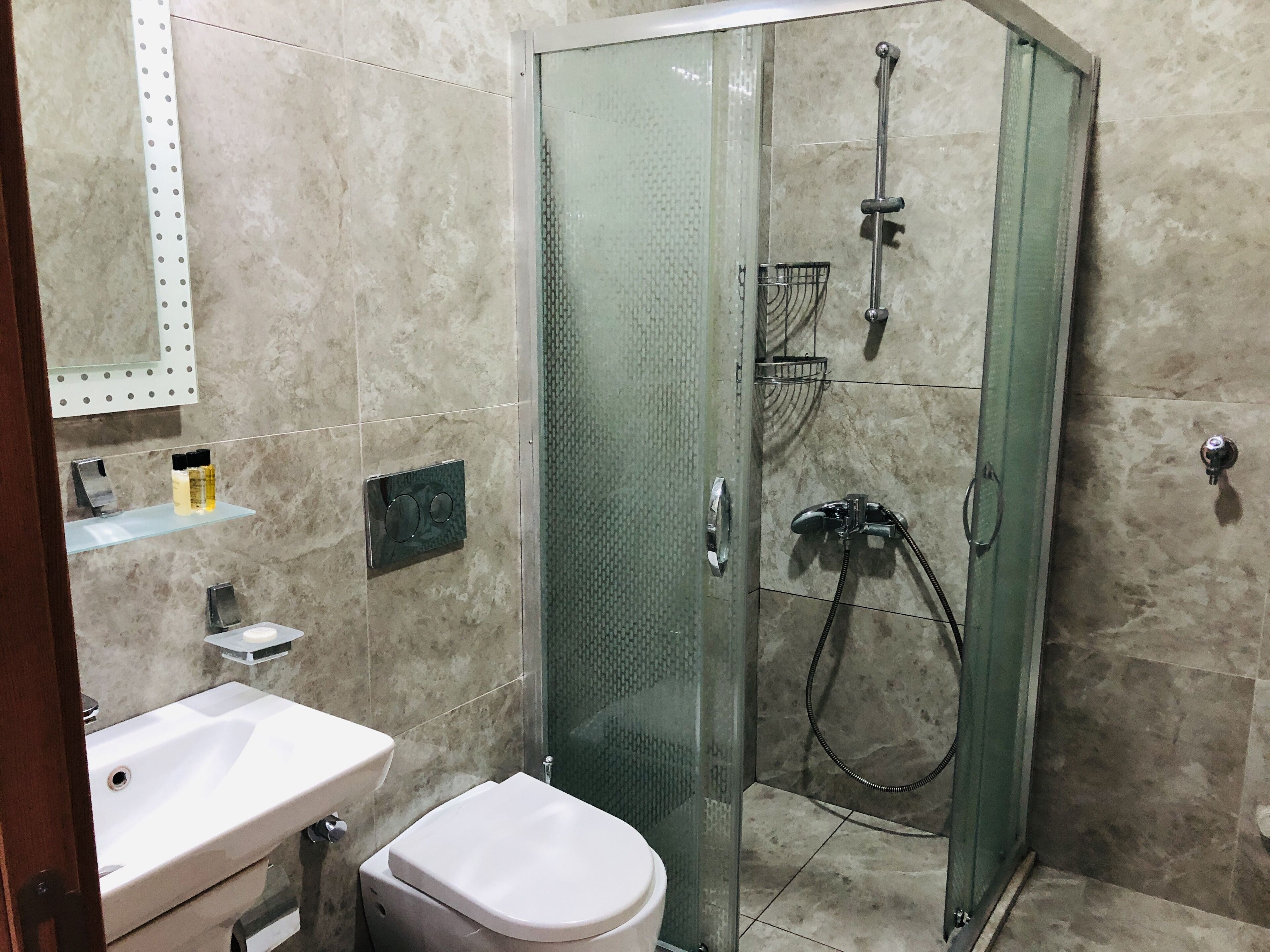 A modern bathroom with a glass-enclosed shower, a white sink, and a toilet.