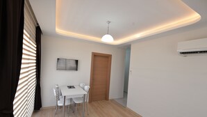 A modern dining area with a white table and chairs, a ceiling light, and an air conditioning unit. - Artim Exclusive Apart Hotel (Fethiye)
