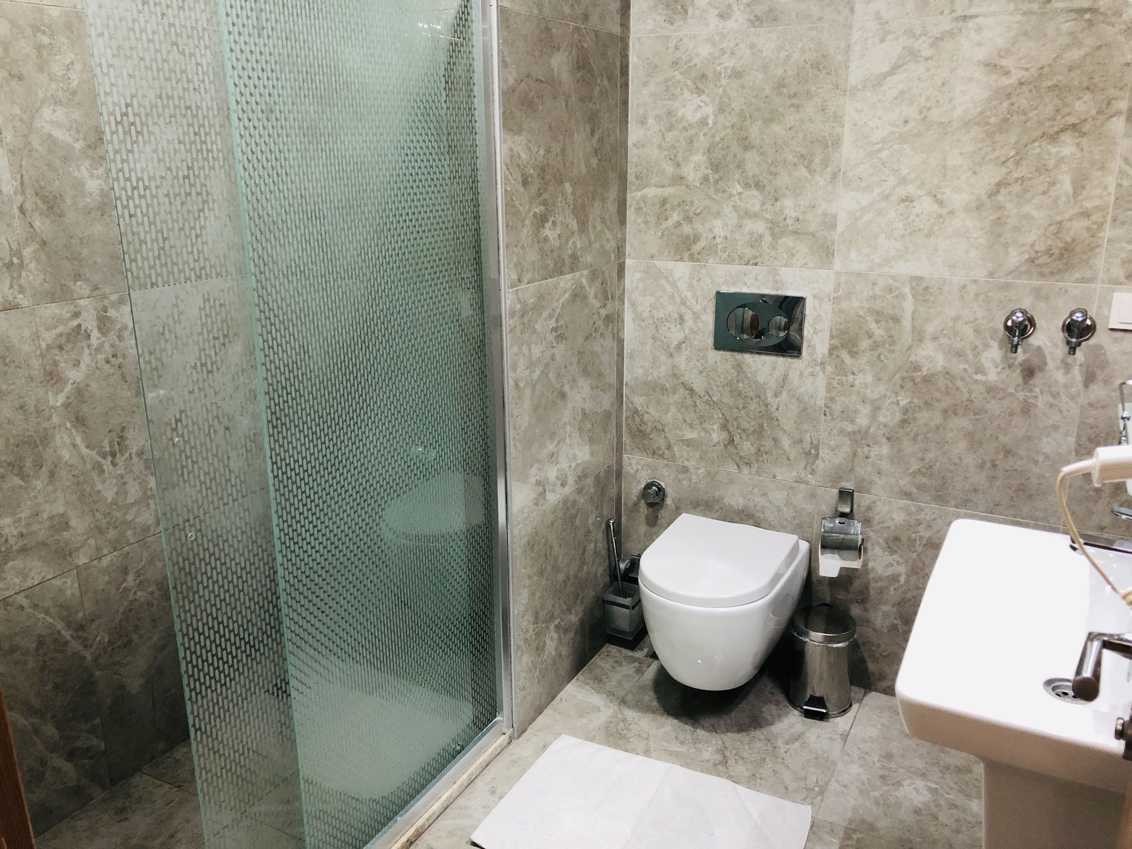 Ein Badezimmer mit Glasdusche, Toilette, Waschbecken und Spiegel.