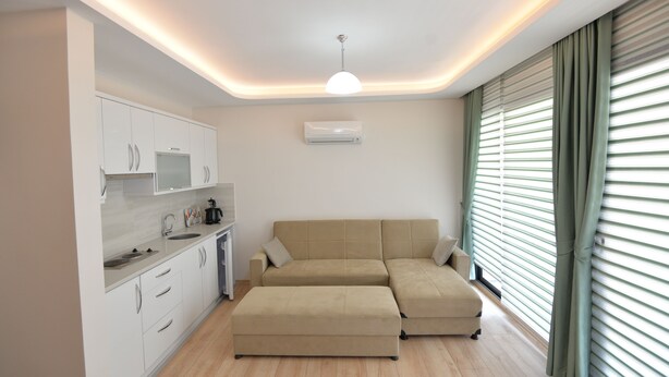 A modern living space with a kitchen, a beige sectional sofa, and a ceiling with recessed lighting. - Artim Exclusive Apart Hotel (Fethiye)