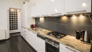 Une cuisine moderne avec des meubles blancs, un évier en acier inoxydable et un plan de travail en bois.