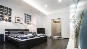 Une chambre à coucher moderne avec un grand lit, un dressing et une douche en verre.