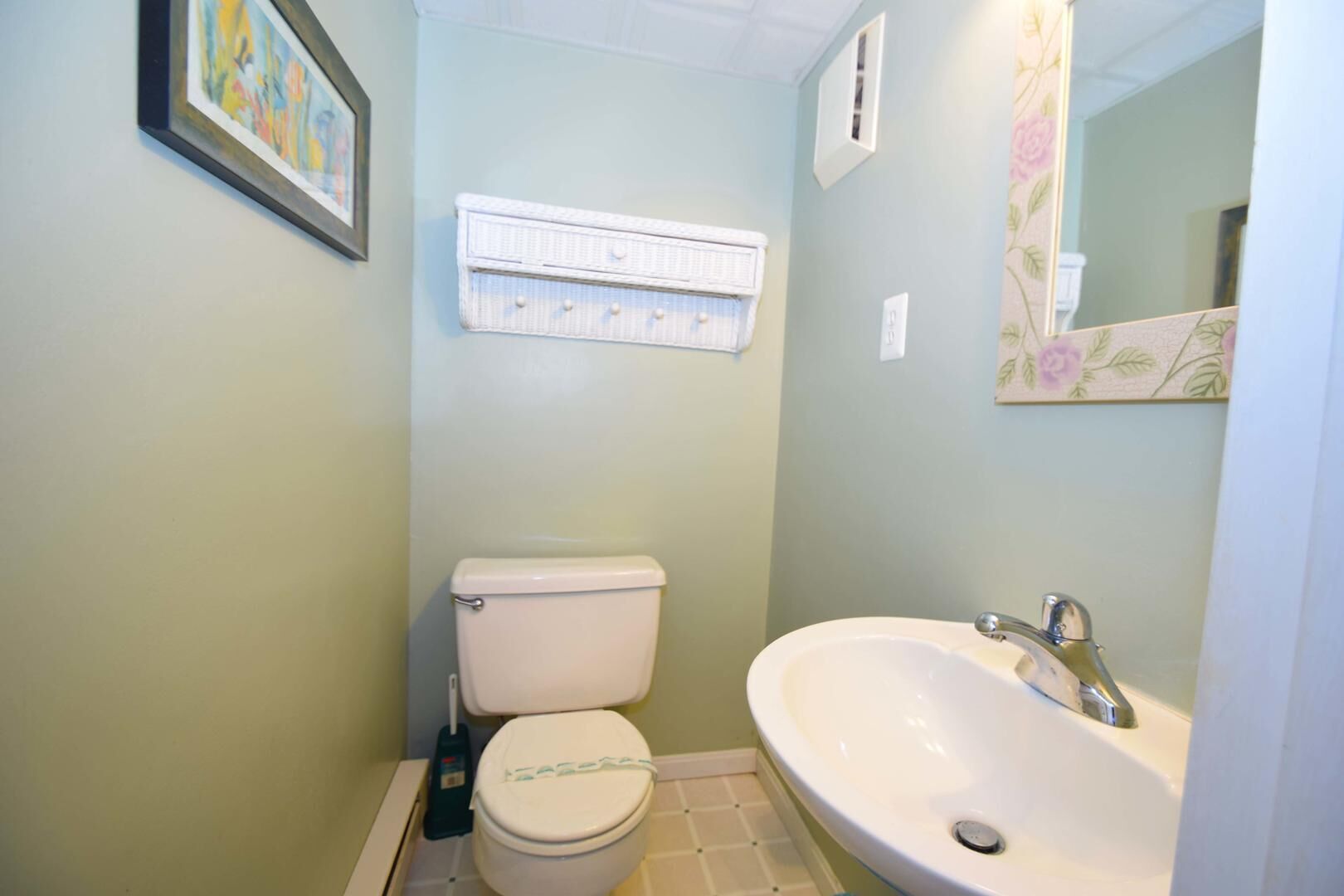 A small bathroom with a toilet, a sink, and a mirror.