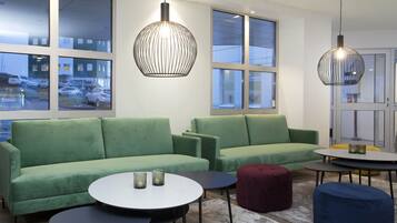 A modern living room with green sofas, round coffee tables, and pendant lighting.