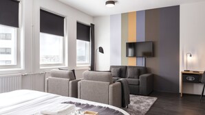 A hotel room with a bed, massage chairs, a TV, and a desk with a lamp. - 201 Hotel (Kópavogur)