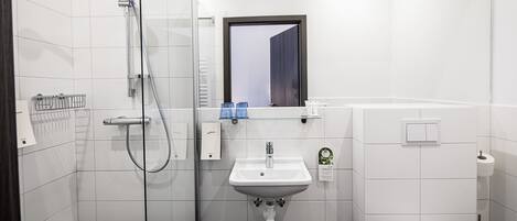 A modern bathroom with a glass-enclosed shower, a white sink, and a toilet.