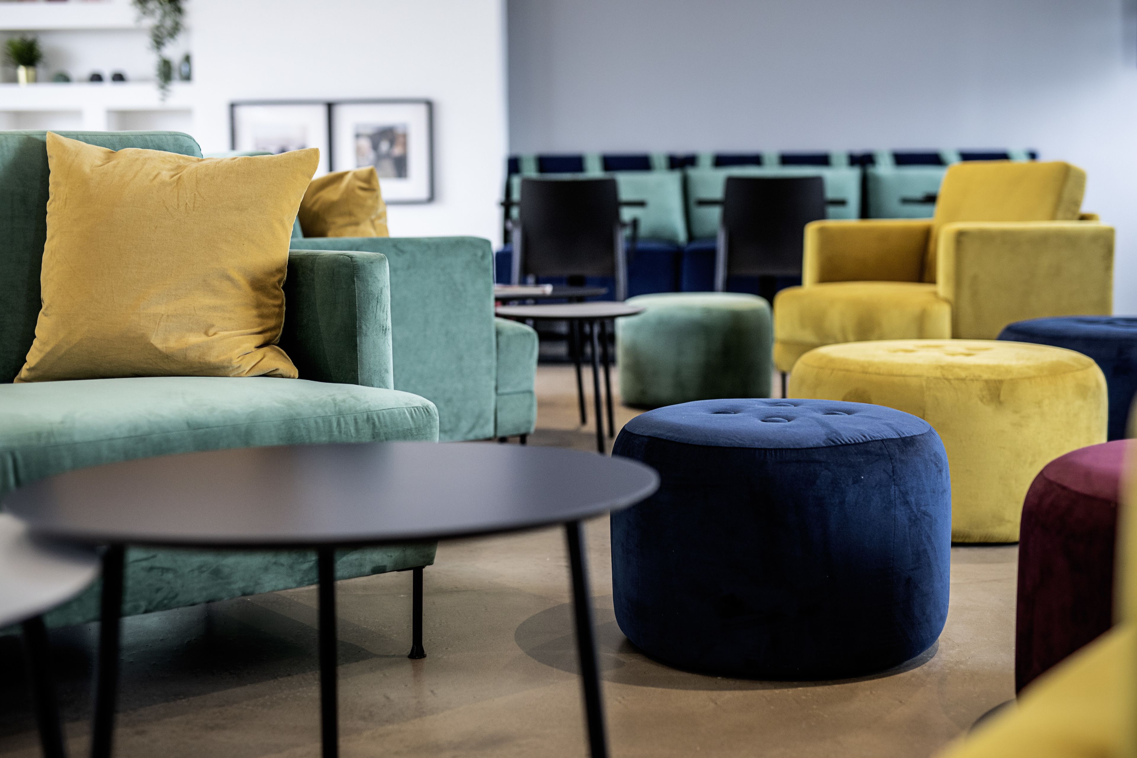 Una sala de estar moderna con un sofá verde, un reposapiés azul y un sillón amarillo.