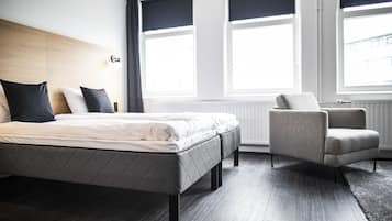 A modern bedroom with a bed, a chair, and large windows.