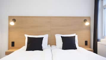 A double bed with white and black bedding, a wooden headboard, and two bedside lamps.