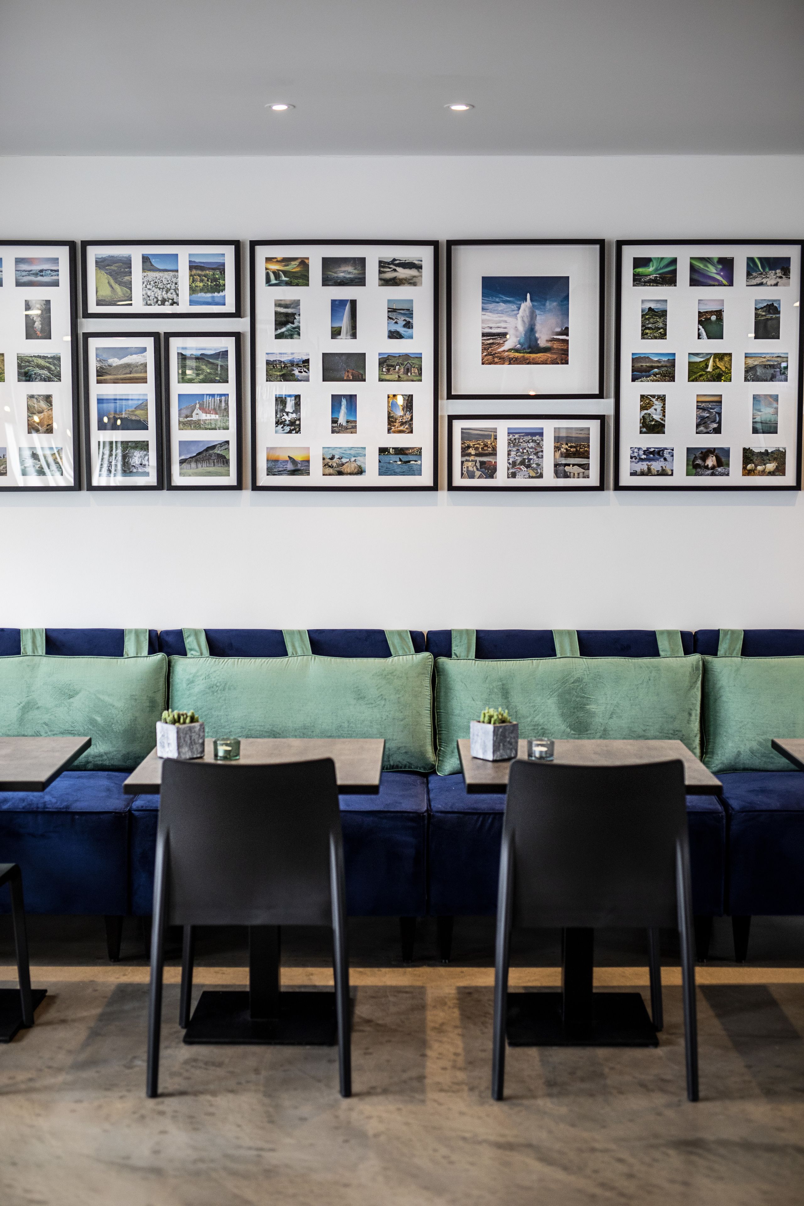 A seating area with a blue sofa and two chairs, framed pictures on the wall, and small tables with candles.