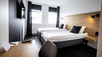 Habitación de hotel con dos camas, un escritorio, una silla, un televisor y una ventana con cortinas.