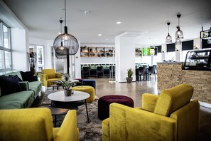 A modern interior with a green sofa, yellow armchairs, and a round coffee table. - 201 Hotel (Kópavogur)